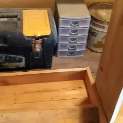Costruzione di una mangiatoia per galline fai da te. In primo piano, una struttura in legno grezzo. Sullo sfondo, una cassetta degli attrezzi, contenitori a cassetti e una livella.