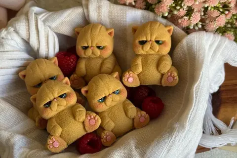 Dolci gatti pallas, con espressioni buffe e zampine rosa, riposano in un cesto tra lamponi rossi e fiori rosa.