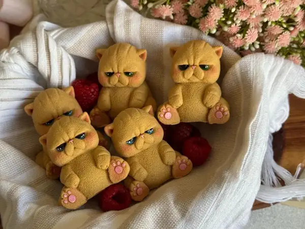 Dolci gatti pallas, con espressioni buffe e zampine rosa, riposano in un cesto tra lamponi rossi e fiori rosa.